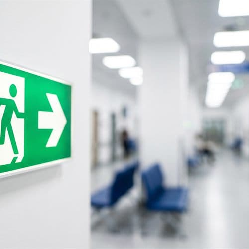 Señal de salida de emergencia instalada en el pasillo de un edificio